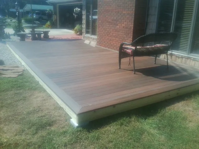 New wood deck and wicker chair beside a brick house in Clifton