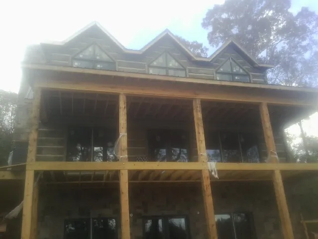 Dormers and porch framing on a large log home under construction — Roof Coating work by our crew in Clifton